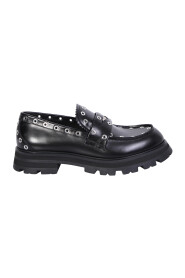 Loafers made of leather with a shiny finish enriched with studs and metal logo detail on the mask by Alexander McQueen